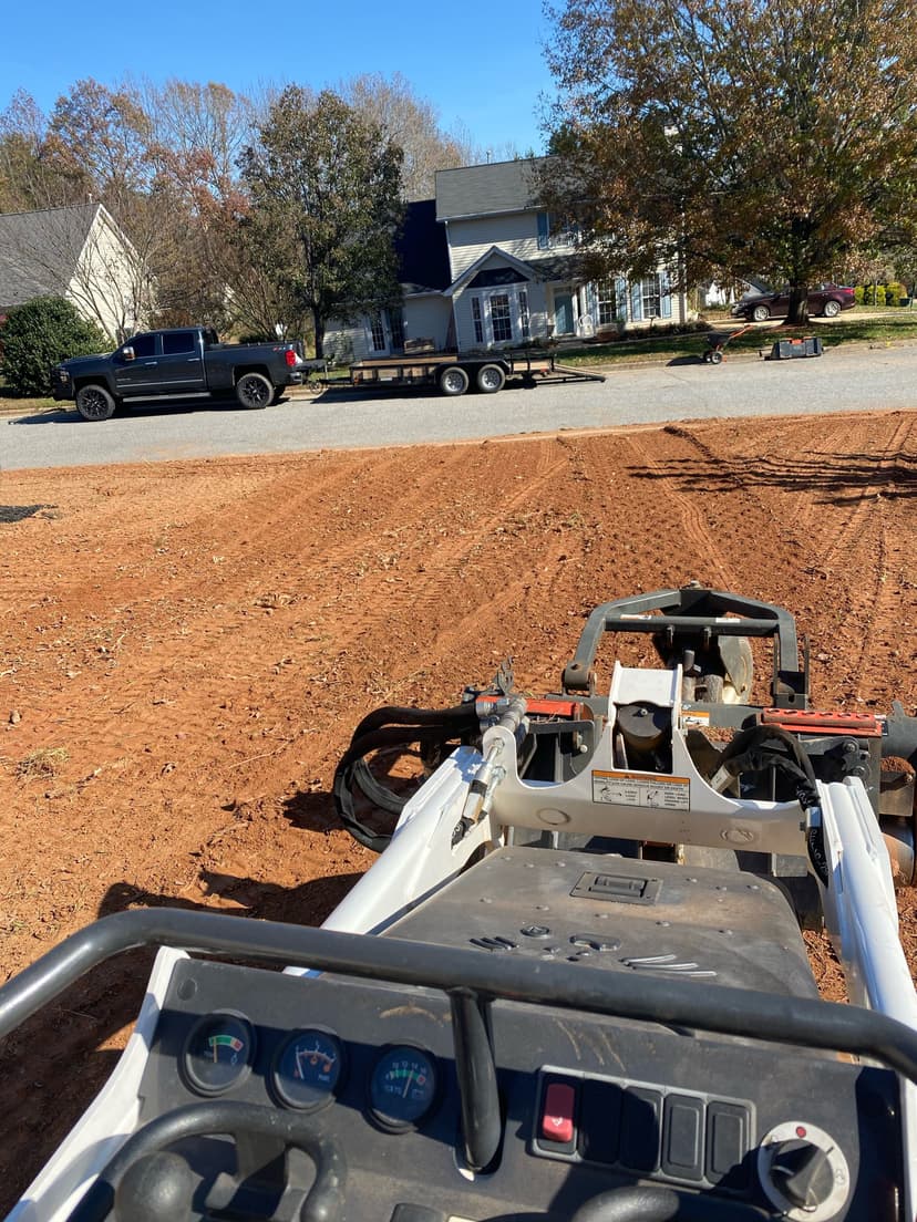 View from a tiller on freshly prepared soil, truck and trailer parked nearby.