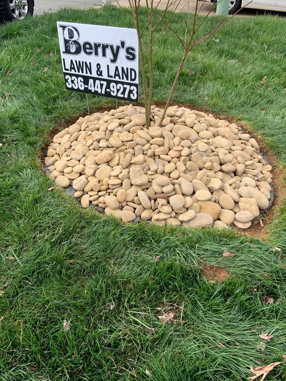 Berry's Lawn and Land sign surrounded by decorative rocks and green grass. Phone: 336-447-9273.